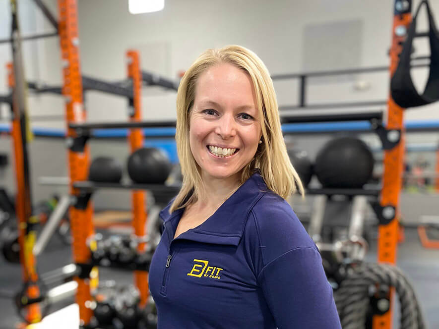 Woman smiling at gym with fitness equipment.