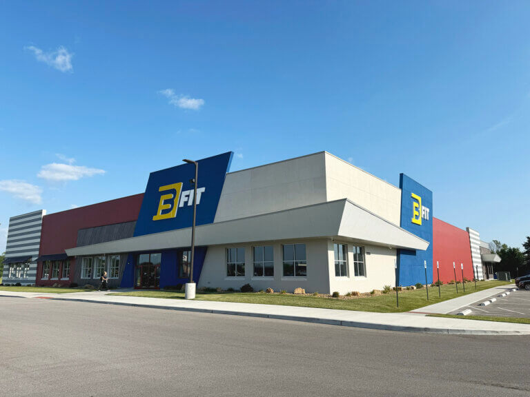 Modern gym building with logo, blue sky background.