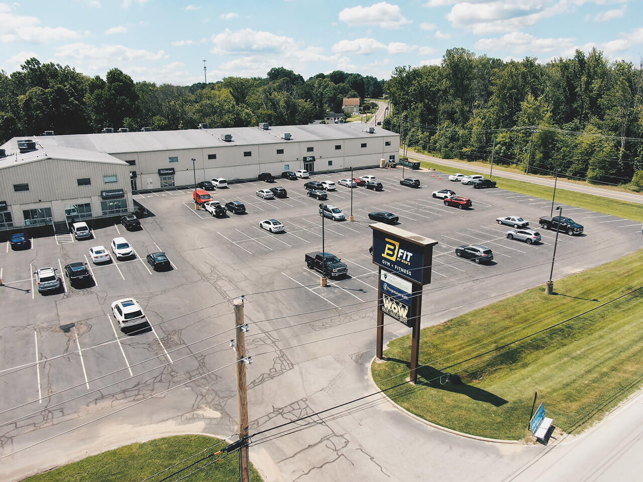 Gym parking lot with cars and trees.