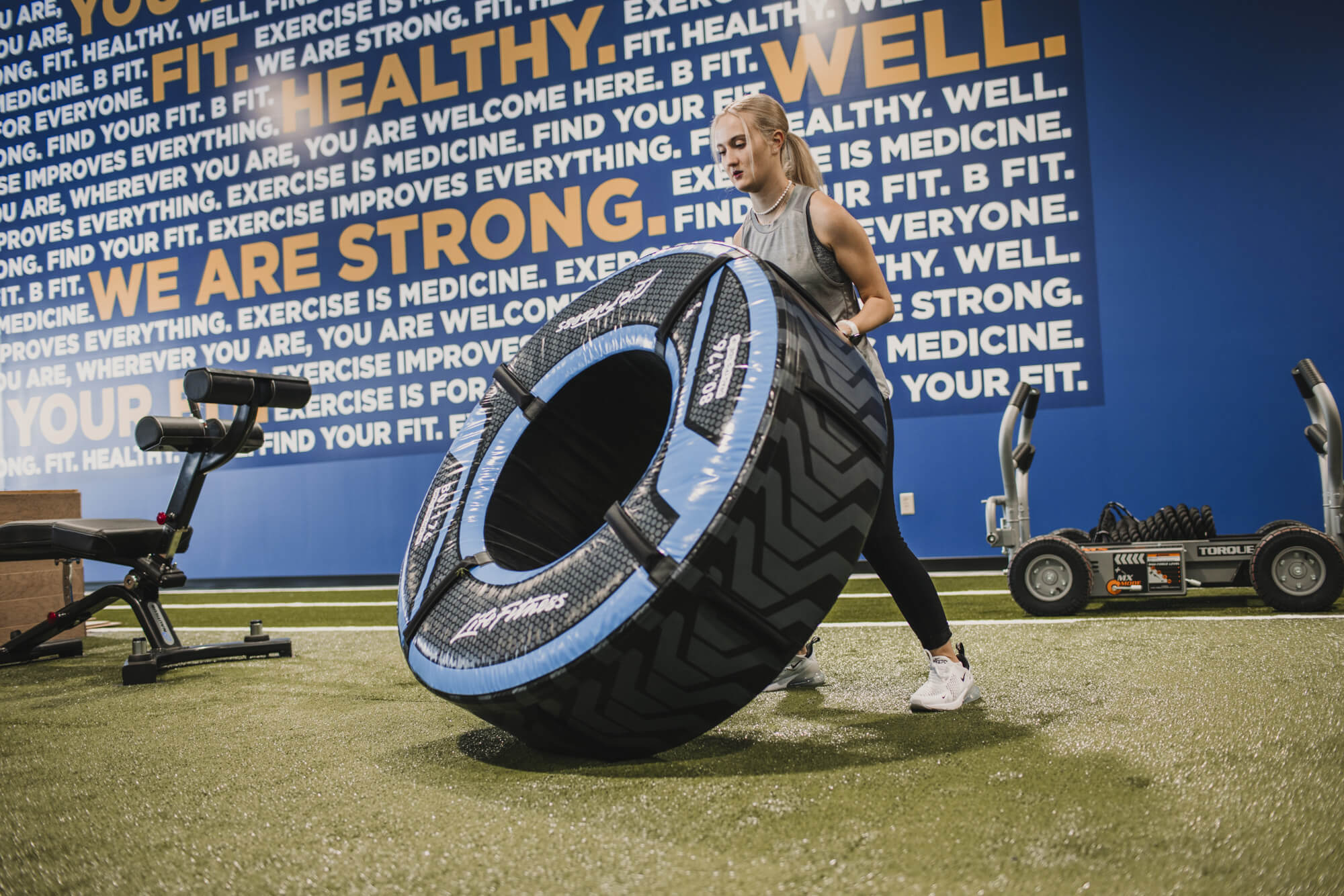 Woman flipping large tire in gym.