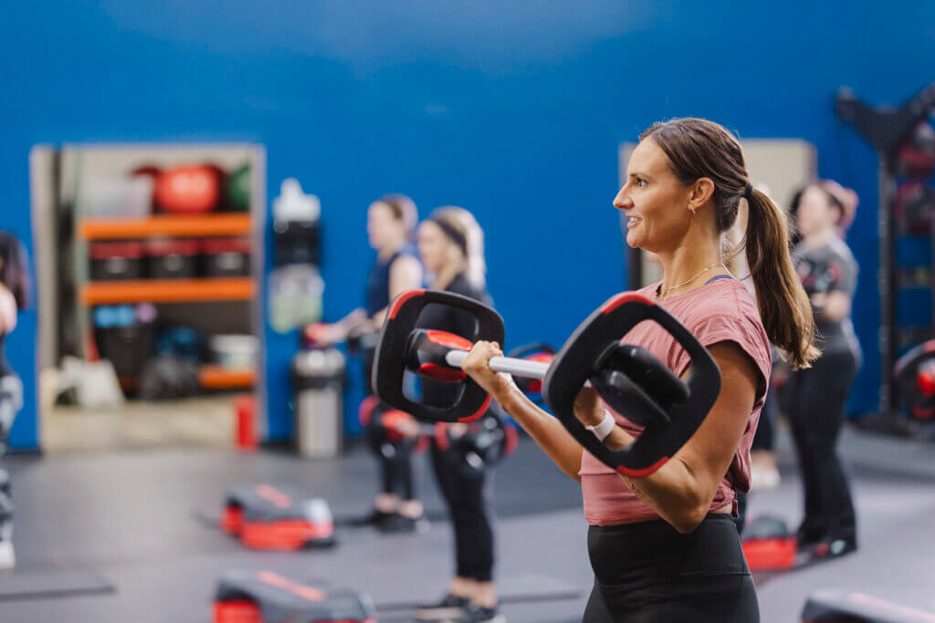 Member of BFit gym in Evansville strength training at Les Mills BODYPUMP group fitness class